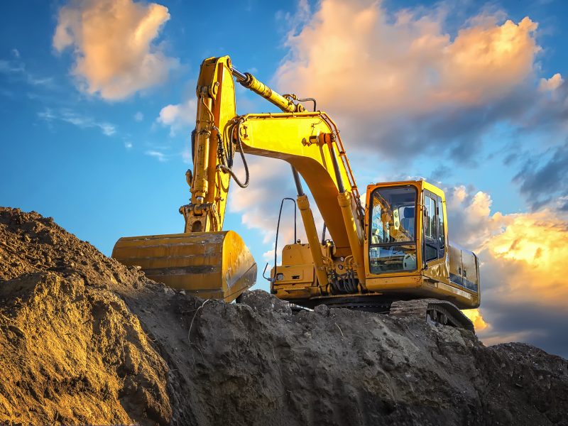 A stopping yellow excavator at an incredibly beautiful sunset