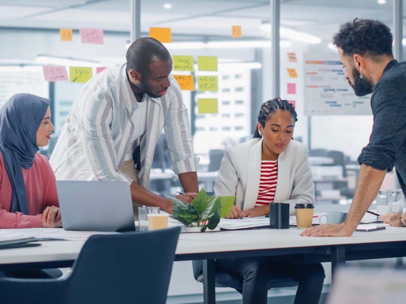 Group of people working together in a conference room with a computer.